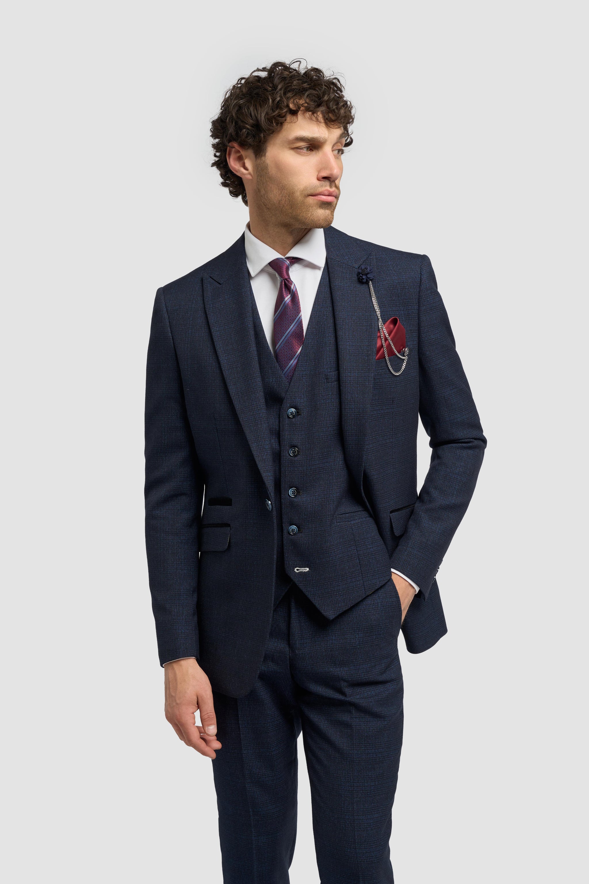 Man klädd i marinblå kostym med röd näsduk mot ljusgrå bakgrund