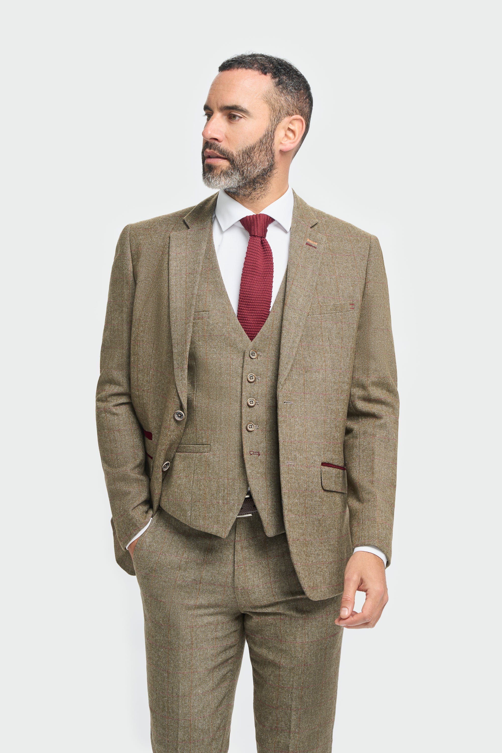 Man klädd i brun kostym med röd slips mot vit bakgrund